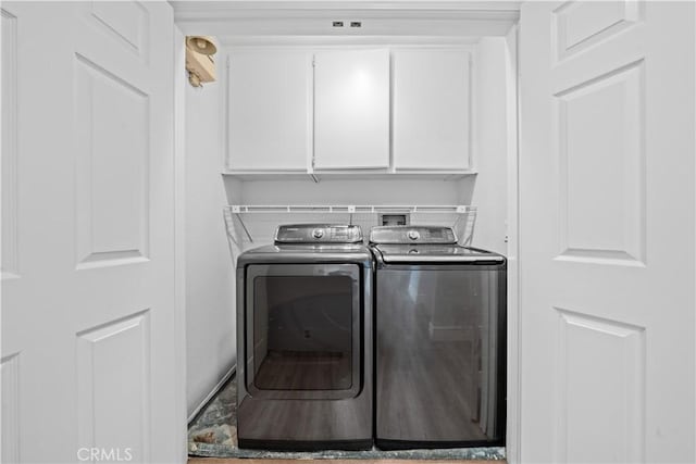 washroom featuring cabinet space and washer and clothes dryer