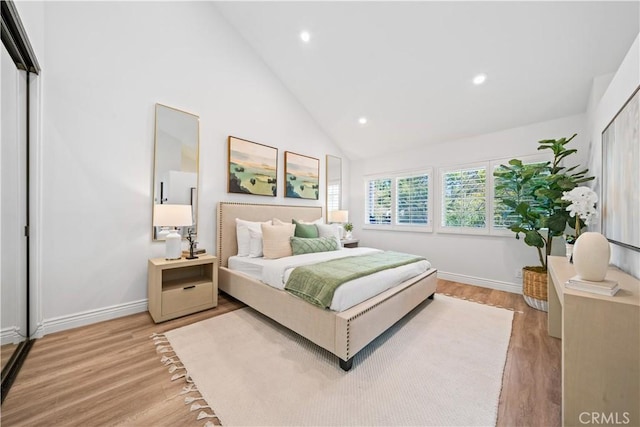 bedroom featuring high vaulted ceiling, light wood-type flooring, and baseboards