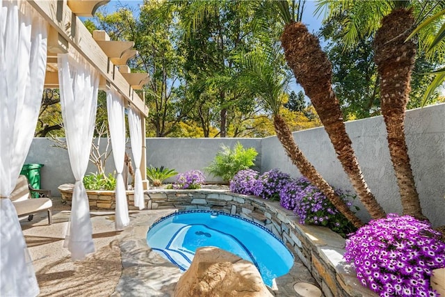 view of swimming pool with a fenced backyard and an in ground hot tub