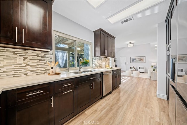 kitchen featuring dark brown cabinetry, a sink, visible vents, light wood-style floors, and dishwasher