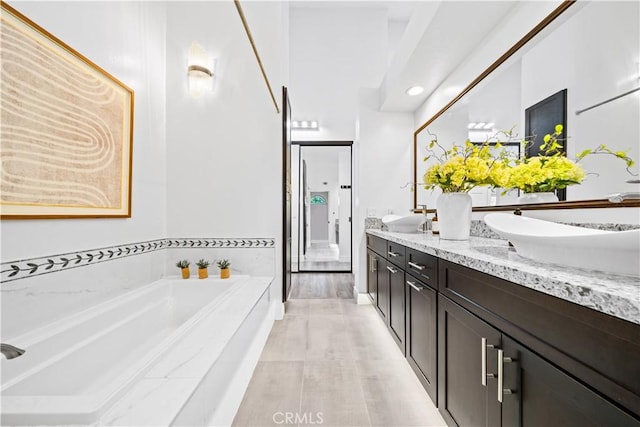 full bathroom featuring double vanity, a sink, and a bath