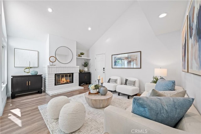 living room featuring a brick fireplace, high vaulted ceiling, wood finished floors, and recessed lighting