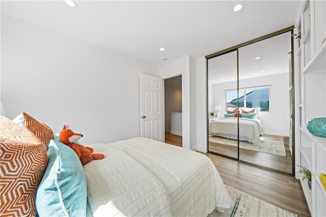 bedroom with baseboards, a closet, light wood-style flooring, and recessed lighting