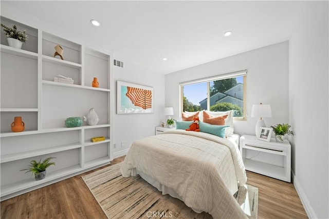 bedroom featuring wood finished floors, visible vents, and baseboards