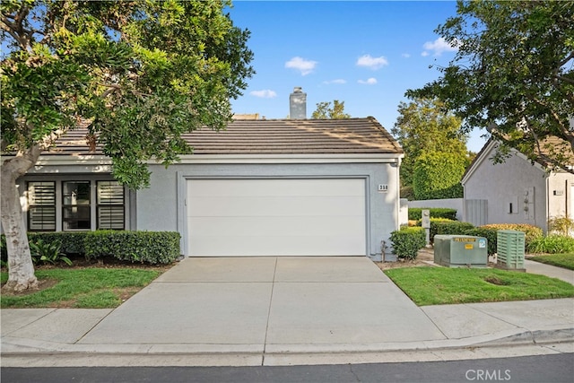 view of front facade featuring a chimney, stucco siding, a garage, driveway, and a tiled roof