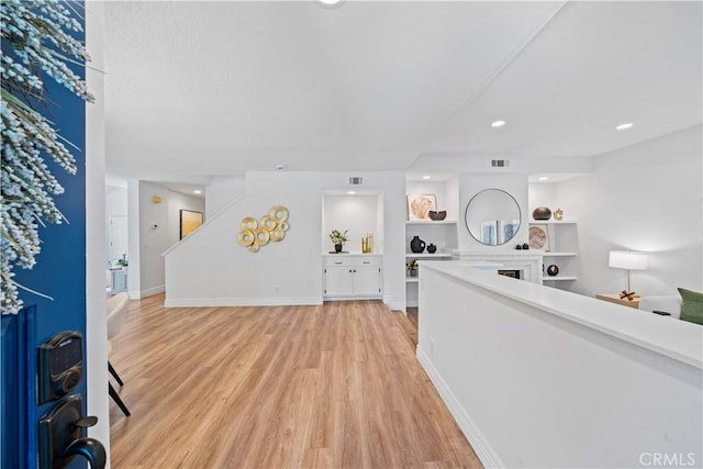 foyer entrance featuring visible vents, light wood-style flooring, baseboards, and stairs