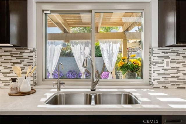 details featuring tasteful backsplash, dark brown cabinets, light countertops, and a sink