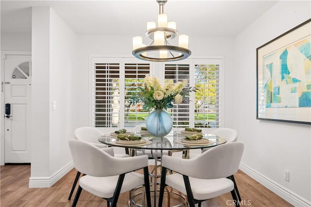 dining area featuring baseboards, light wood-type flooring, and a notable chandelier