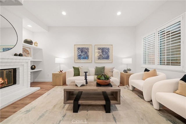 living room featuring recessed lighting, built in shelves, wood finished floors, and a glass covered fireplace