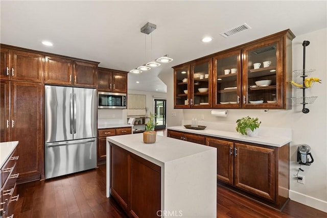 kitchen with dark wood-type flooring, visible vents, light countertops, appliances with stainless steel finishes, and glass insert cabinets