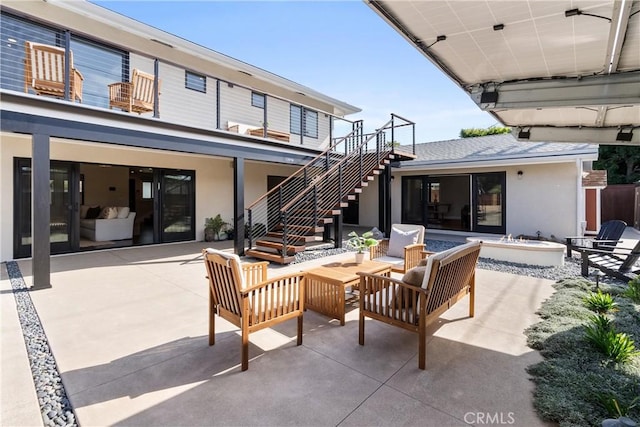 view of patio / terrace with stairs and an outdoor living space with a fire pit