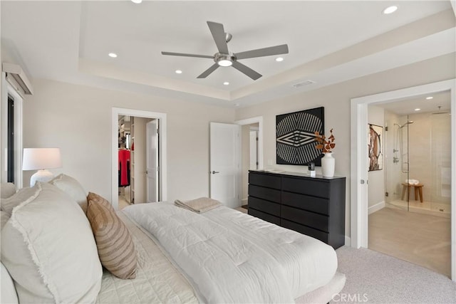 bedroom featuring a walk in closet, recessed lighting, a raised ceiling, light colored carpet, and connected bathroom