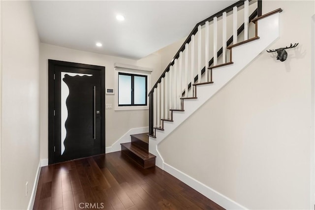 entryway with dark wood-type flooring, elevator, baseboards, and stairs