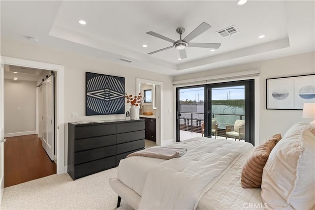 bedroom with baseboards, a tray ceiling, visible vents, and access to exterior