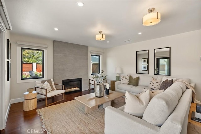 living area with dark wood-type flooring, recessed lighting, baseboards, and a tiled fireplace