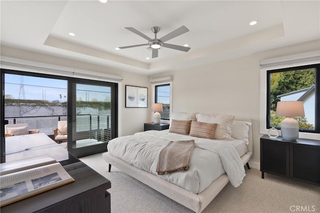 bedroom featuring a tray ceiling, access to outside, light colored carpet, and recessed lighting