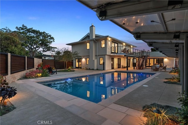 pool at dusk with a fenced in pool, a patio area, fence, and stairway