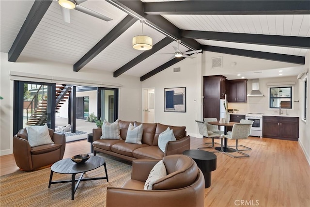 living area featuring lofted ceiling with beams, light wood-style floors, ceiling fan, and visible vents