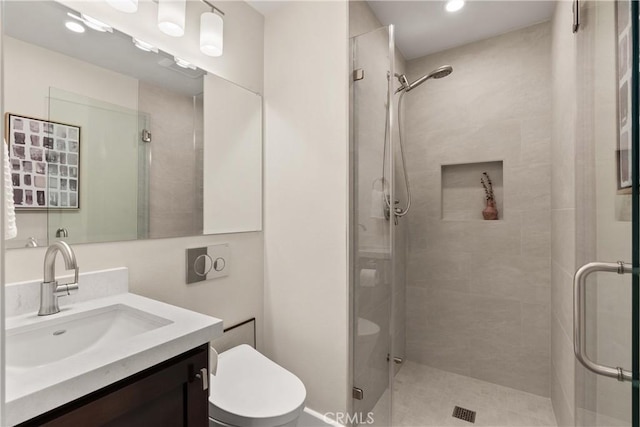 bathroom featuring vanity, a shower stall, and toilet