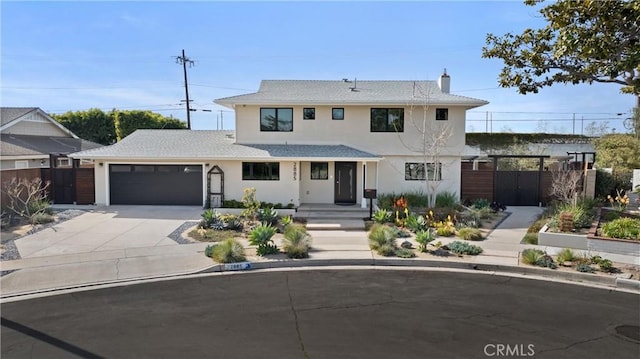 view of front of property with concrete driveway, fence, an attached garage, and stucco siding