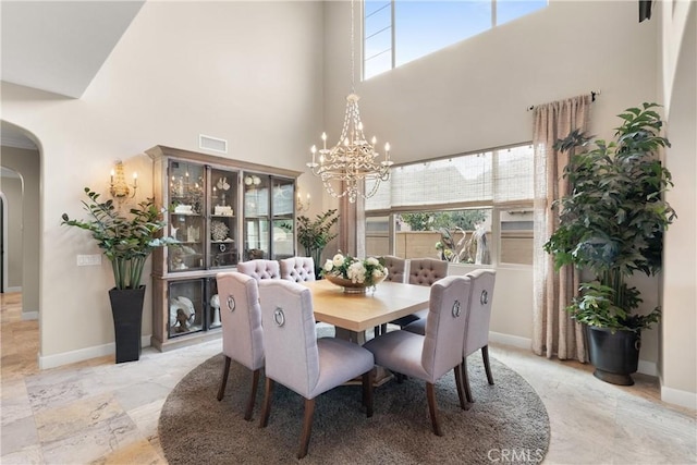 dining room with arched walkways, visible vents, an inviting chandelier, and a wealth of natural light