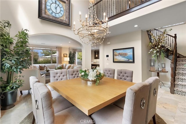 dining space featuring stairs, recessed lighting, a towering ceiling, arched walkways, and a notable chandelier