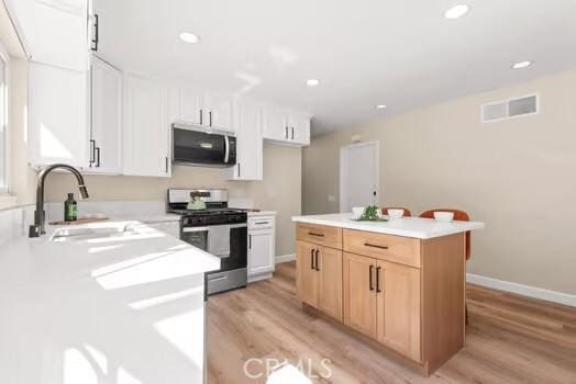 kitchen featuring stainless steel appliances, light countertops, visible vents, a sink, and light wood-type flooring