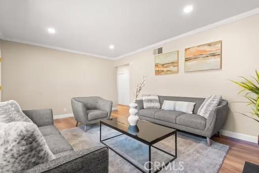 living area featuring ornamental molding, recessed lighting, baseboards, and wood finished floors