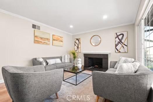 living area featuring ornamental molding, a fireplace, wood finished floors, and recessed lighting