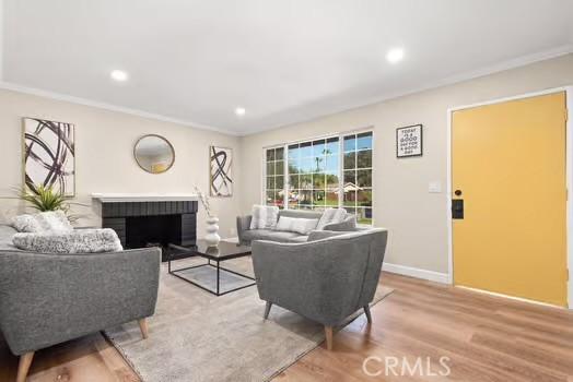 living area featuring baseboards, ornamental molding, wood finished floors, and recessed lighting