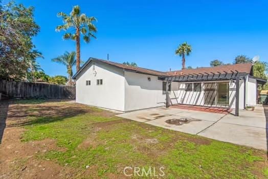 back of property with a lawn, a patio, fence, a pergola, and stucco siding