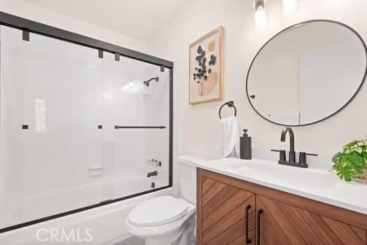 bathroom with toilet, combined bath / shower with glass door, and vanity