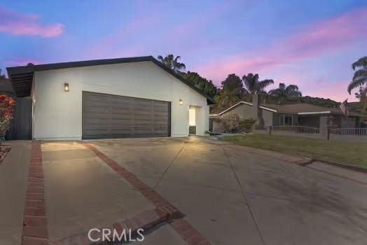 view of front of home with concrete driveway, an attached garage, and stucco siding