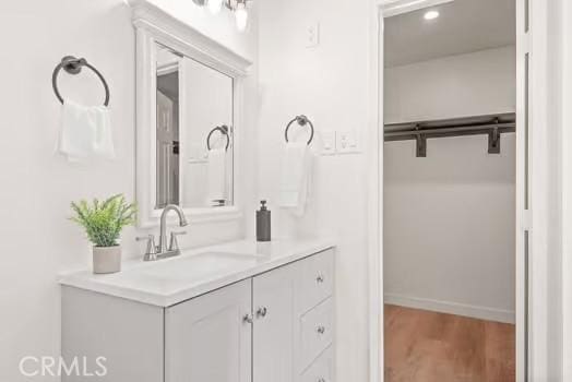 bathroom with wood finished floors, vanity, and baseboards