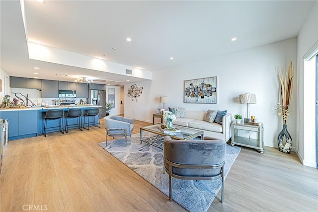 living area with light wood finished floors, visible vents, and recessed lighting