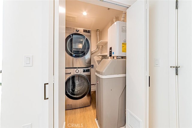 clothes washing area featuring visible vents, laundry area, stacked washer / dryer, and light wood-style flooring