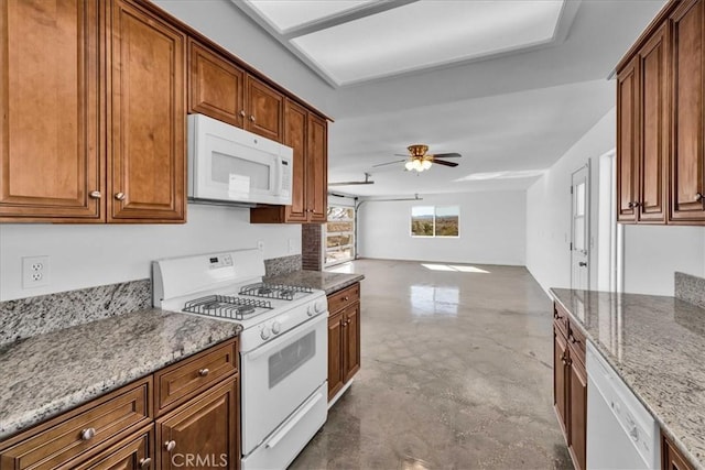 kitchen with white appliances, brown cabinetry, a ceiling fan, light stone counters, and open floor plan