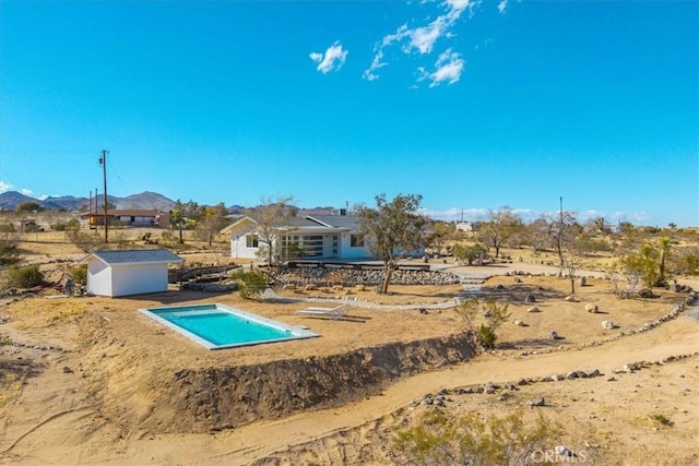 view of pool with a mountain view, an outdoor structure, and a shed