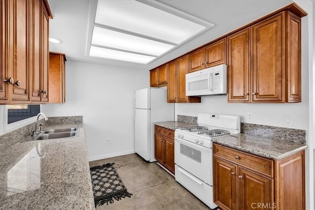 kitchen with white appliances, baseboards, brown cabinetry, and a sink