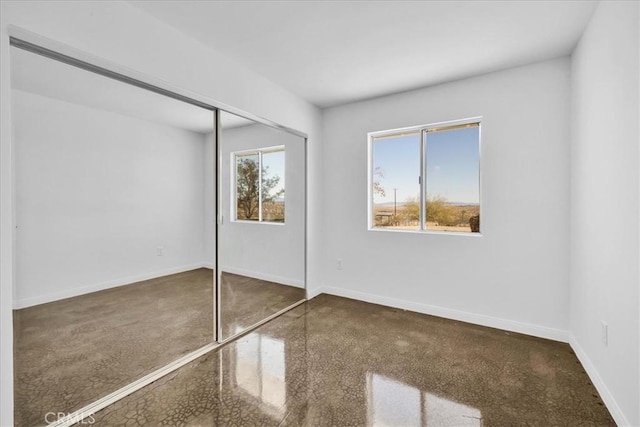 unfurnished bedroom featuring multiple windows, a closet, and baseboards