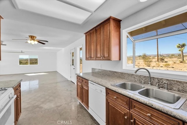 kitchen featuring white appliances, a ceiling fan, light stone counters, brown cabinets, and a sink