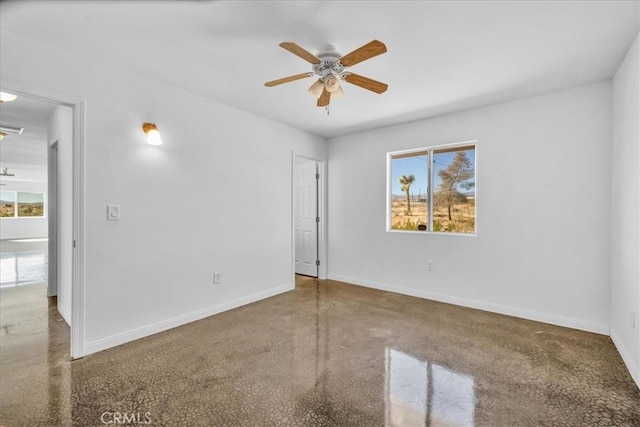 unfurnished room with finished concrete floors, baseboards, and a ceiling fan