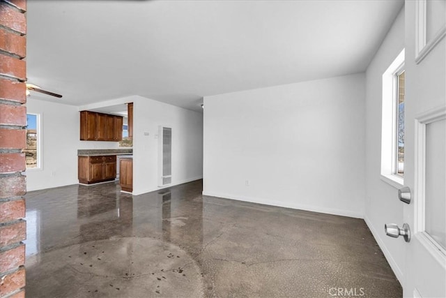 unfurnished living room featuring finished concrete flooring and baseboards