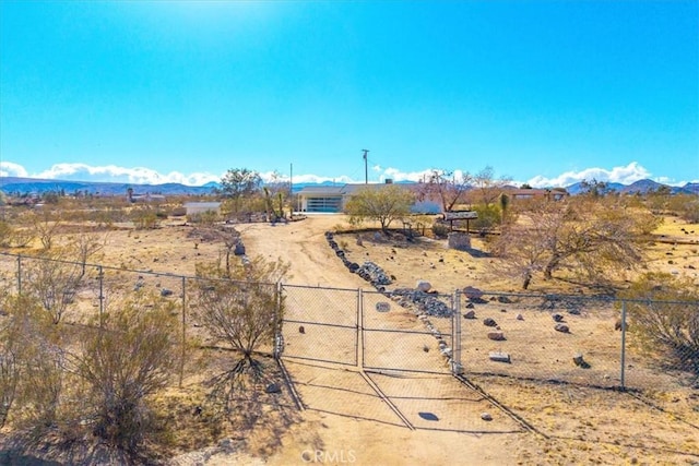 view of yard featuring a gate, fence, a mountain view, and a rural view