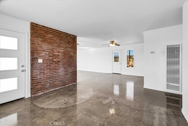 interior space featuring brick wall, a heating unit, a wealth of natural light, and a ceiling fan