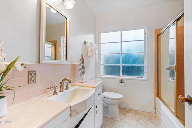 full bath featuring plenty of natural light, vanity, toilet, and bath / shower combo with glass door