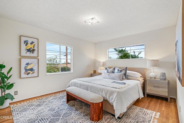 bedroom with a textured ceiling, baseboards, and wood finished floors