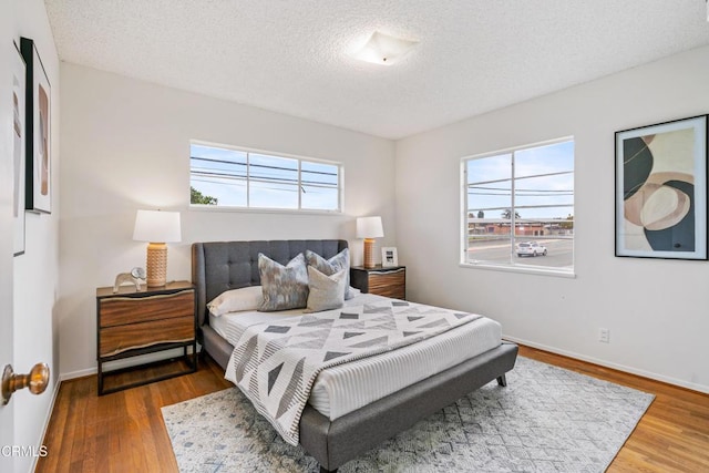 bedroom featuring a textured ceiling, wood finished floors, and baseboards