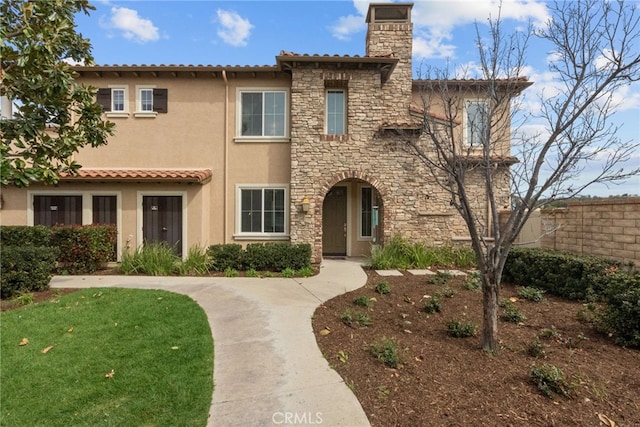 view of front of property with stone siding, a chimney, and stucco siding