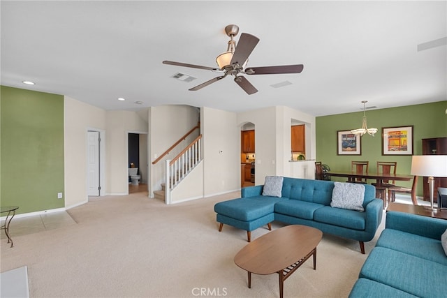 living area with arched walkways, light carpet, visible vents, a ceiling fan, and stairs